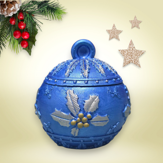 Blue decorative ornament with silver holly design on a beige background with Christmas decorations.