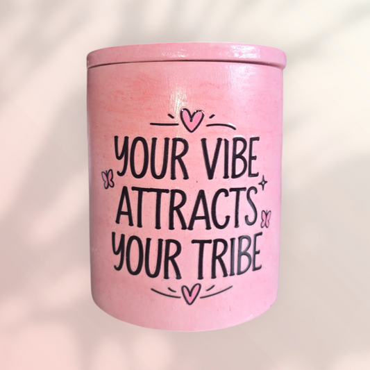 Handmade pink candle vessel with the text "your vibe attracts your tribe" on it. 